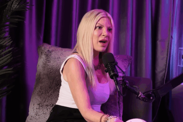 Tori Spelling speaks under beautiful purple lighting.