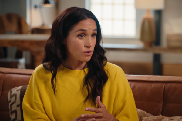 Meghan Markle in a yellow blouse while chatting.