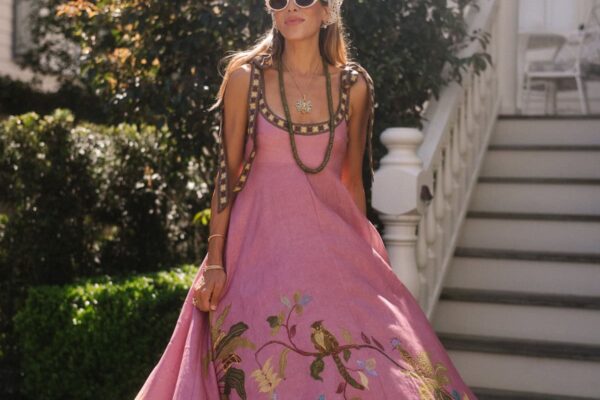 Beautiful woman in pink embroidered boho resort wear with sunglasses and jewelry.