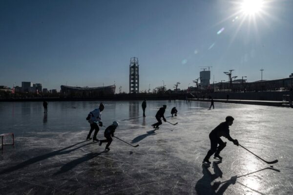 People play hockey on the frozen ice near the National Stadium at Olympic Park on January 13, 2022 in Beijing, China.