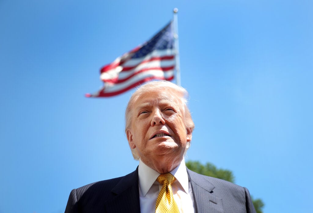 U.S. President Donald Trump speaks in front of the American flag to the press as he departs the White House on May 12, 2026 in Washington, DC.