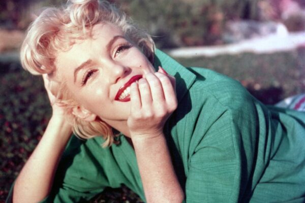 Actress Marilyn Monroe poses for a portrait laying on the grass in 1954 in Palm Springs, California.