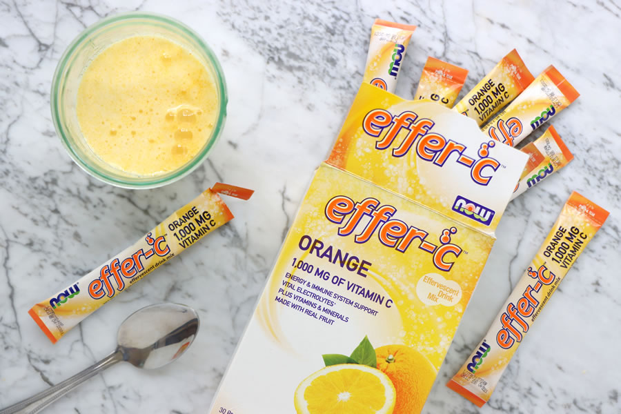 Now Effer-C Orange effervescent vitamin C drink mix next to a glass and spoon for immune support